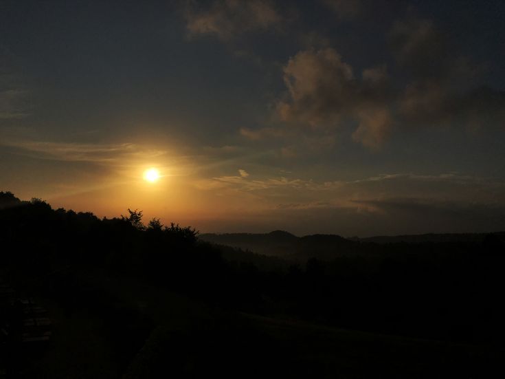 A serene sunset reflecting on green hills and clear clouds, creating a calm and relaxing atmosphere.