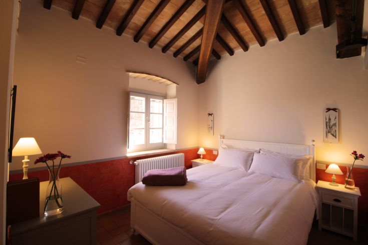 A cozy bedroom with a double bed, simply decorated with warm tones, perfect for a peaceful stay.