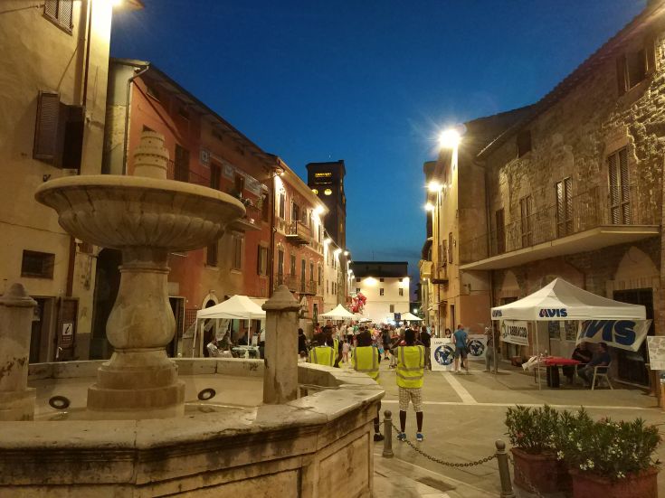 A quiet alley in Deruta, featuring a central fountain and illuminated by soft lights.