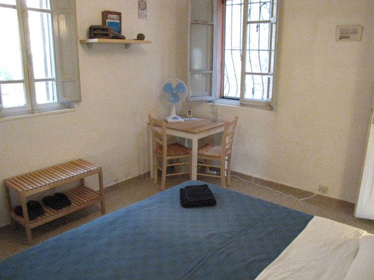 A simple and bright space with large windows, furnished with a table and a bench for comfort.