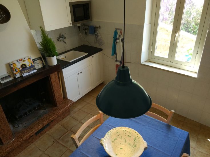 Spacious and bright kitchen featuring a central table and a window allowing natural light.