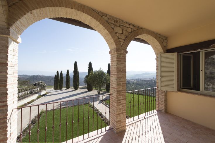 View from a terrace overlooking the Umbrian countryside, featuring arches and cypress trees in the background.