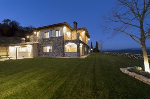 A stone farmhouse surrounded by a well-kept garden, in a serene and natural setting.