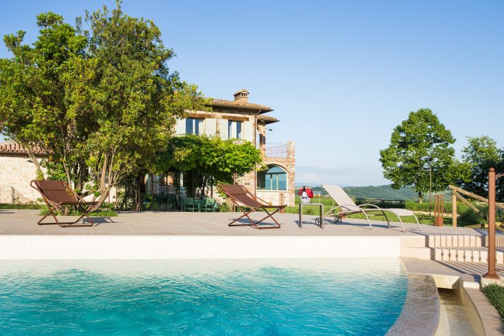 Relaxing moments by the pool in a countryside farmhouse surrounded by tranquil nature.