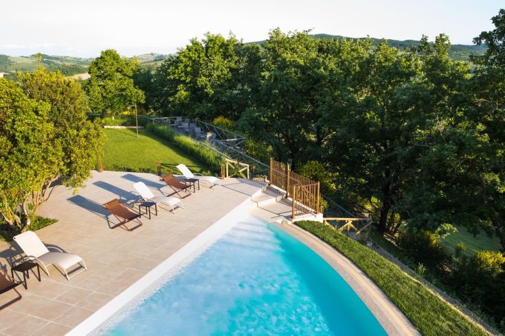 Relax by the pool surrounded by nature, with trees and vineyards in sight.