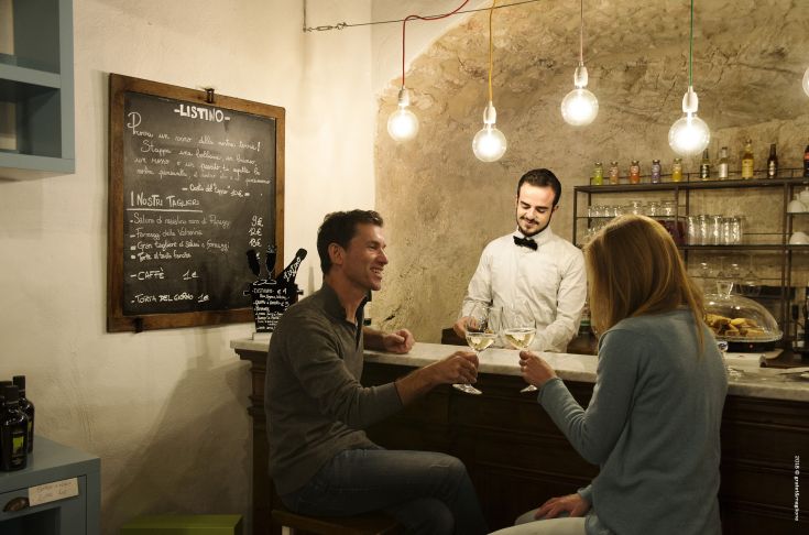 A social moment at a pleasant restaurant, with a waiter serving drinks to customers.