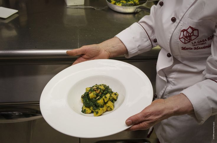 A dish of green gnocchi served on a simple plate, expertly prepared by a chef. Beautifully presented.