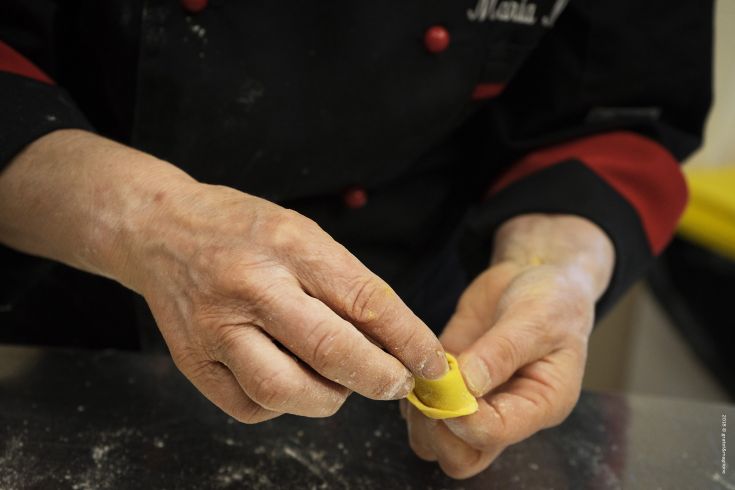 A skilled chef prepares fresh tortellini, showcasing a part of Italian culinary tradition.