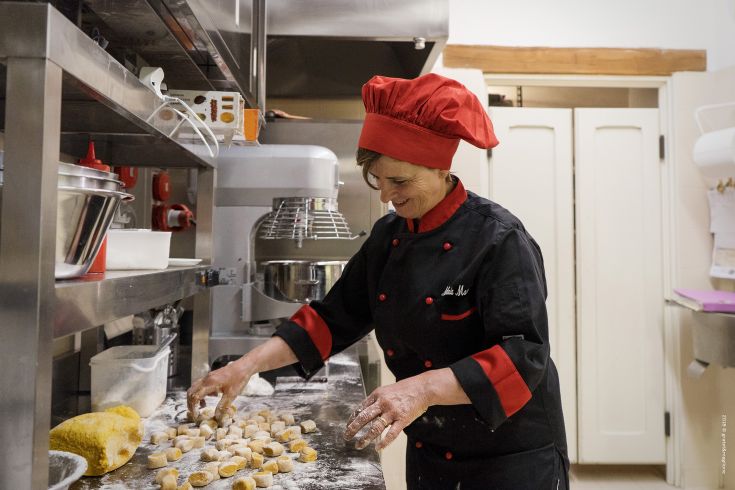 A chef prepares gnocchi in the kitchen using various cooking utensils.
