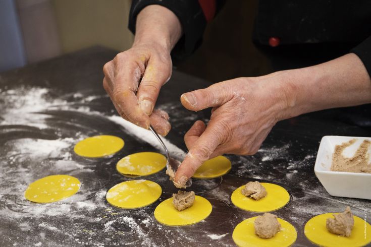 A craftsman prepares ravioli, carefully wrapping dough in a rustic and welcoming setting.
