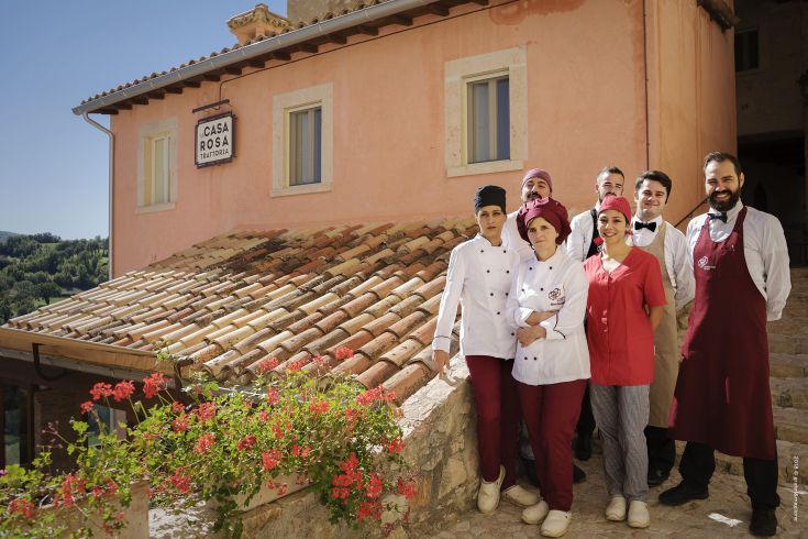 The Casa Rosa restaurant showcases its smiling staff in front of a peaceful medieval village.