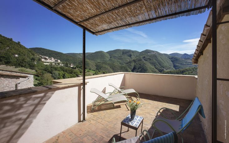 Terrace with a view of green hills and a clear sky, a peaceful spot for relaxing moments.