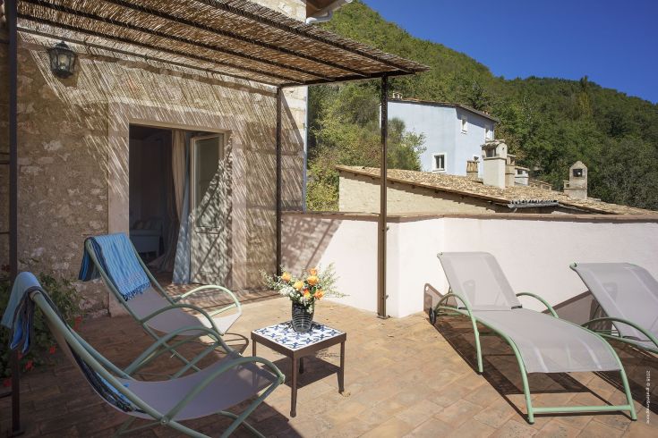 Outdoor terrace for relaxation, furnished with loungers and a table, surrounded by greenery.