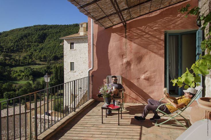 Quiet moments on a terrace in a medieval village, surrounded by greenery and natural landscapes.