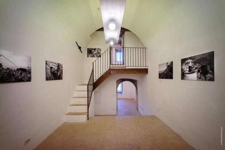 An exhibition space with a staircase and black and white paintings on the walls.