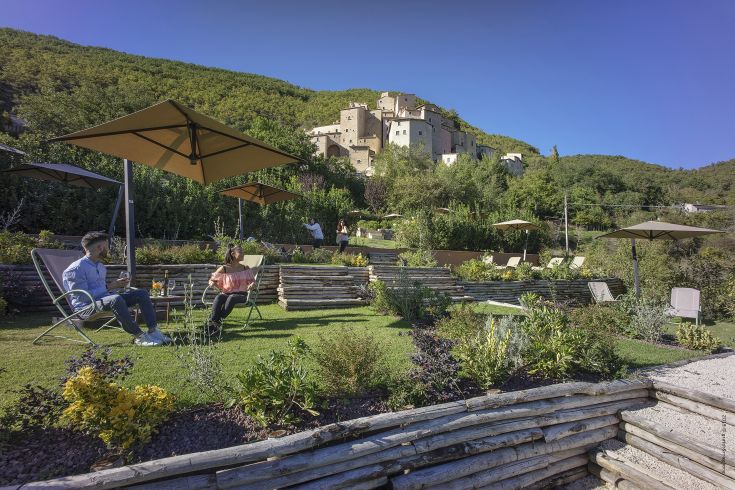 A well-kept garden in the village of Castello di Postignano, providing a beautiful view of the surroundings.