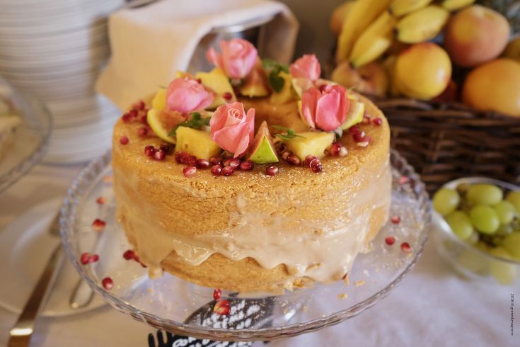 A decorated cake with fresh fruit and rose-shaped finishes, perfect for parties and celebrations.