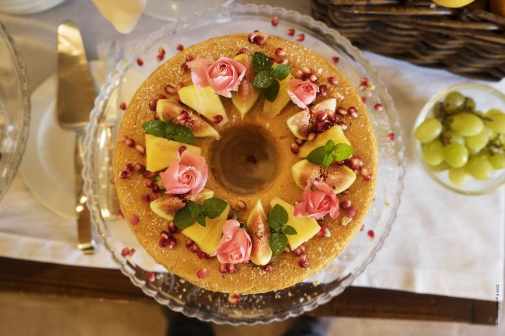 A beautifully decorated cake with roses, fruits, and pomegranate, perfect for special events and celebrations.