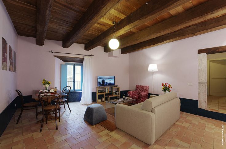 A spacious living room with a fully equipped kitchen and sofa, featuring a bright and welcoming atmosphere.