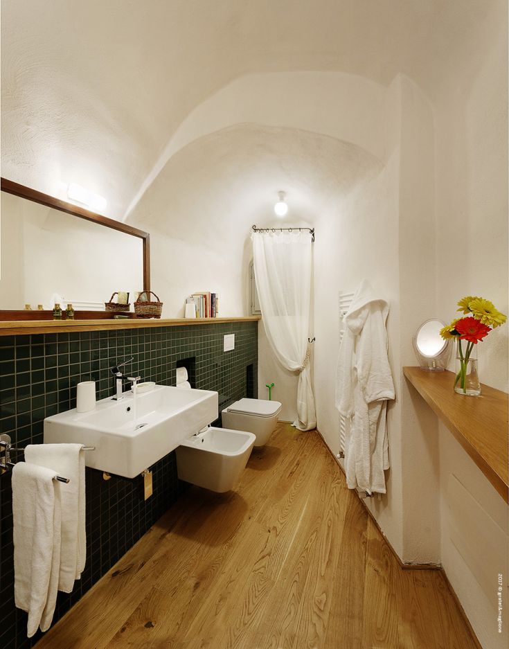 A cozy bathroom with green walls and wooden details, well-lit and functional.