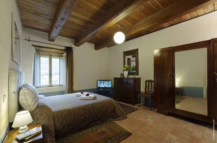 Room with wooden beam ceiling and traditional furniture. Perfect for a peaceful stay in a historic setting.