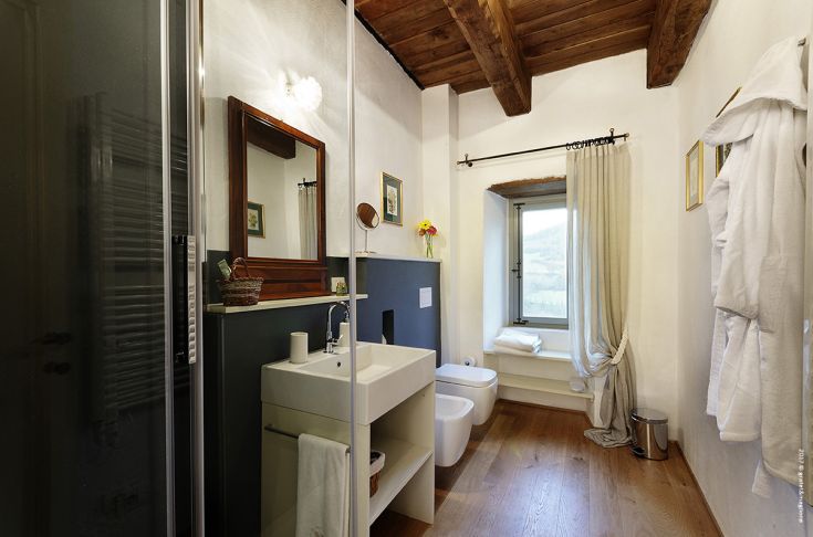 A sober bathroom design featuring a shower, a simple sink, and rustic details in a comfortable atmosphere.
