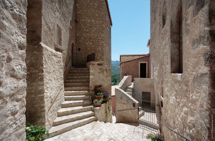 A peaceful alley in the medieval village, with stone buildings and winding stairs.