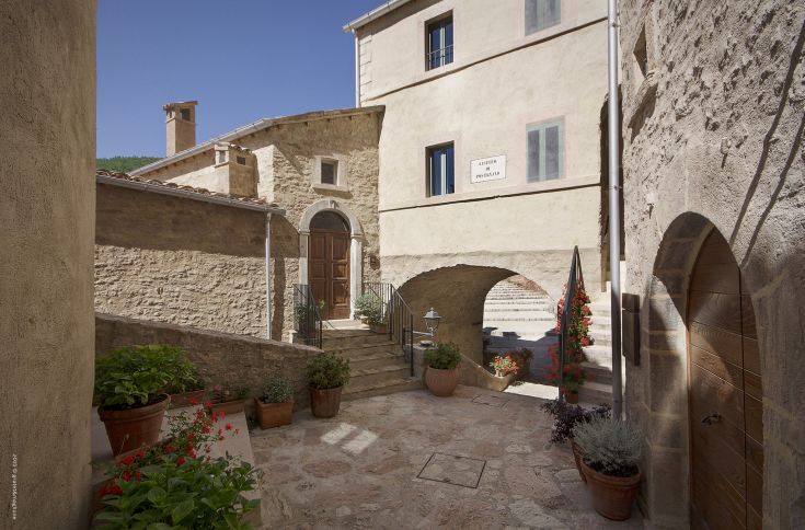 A section of Postignano Castle in Umbria, featuring historic buildings and diverse vegetation.