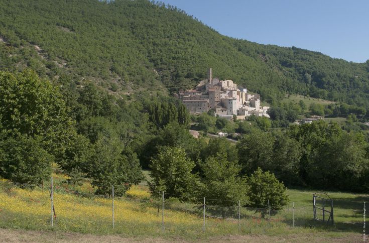 Scene of the medieval village of Postignano, surrounded by the green hills of Umbria.