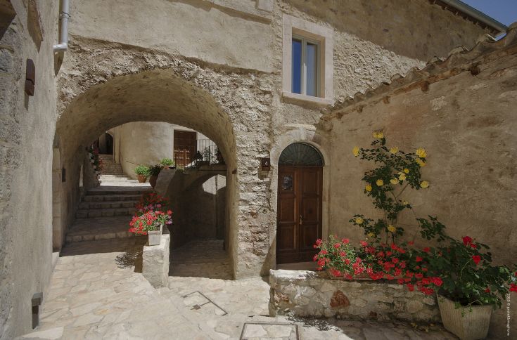 A serene corner of a medieval village, featuring stone arches and flowering plants enhancing the atmosphere.