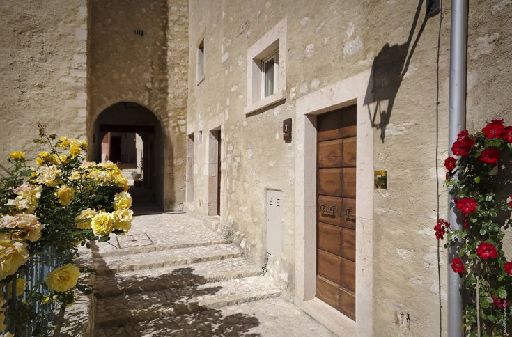 A glimpse of Postignano Castle, featuring colorful flowers and architectural elements typical of the medieval period.