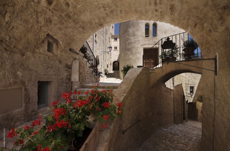 A peaceful corner of a medieval village, adorned with flowers and traditional architectural features.