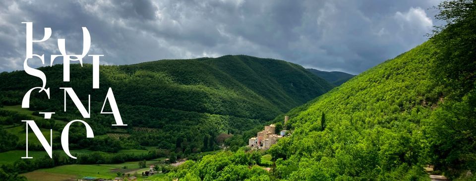 Una scena del borgo medievale di Postignano, immerso nella quiete delle colline verdi circostanti.