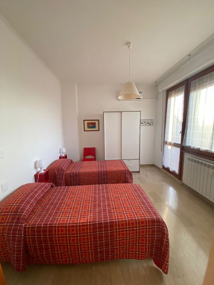 Ein geräumiges, helles Zimmer mit zwei Betten und schlichter Einrichtung.