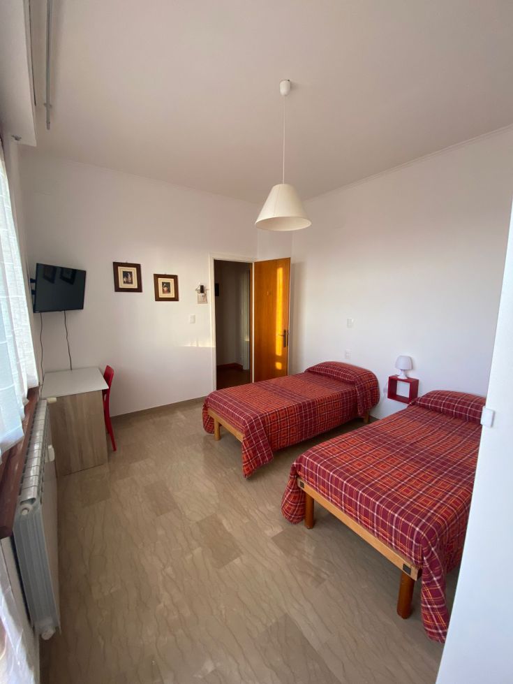 Ein geräumiges und helles Schlafzimmer mit zwei Einzelbetten, Fernseher und modernen Möbeln.