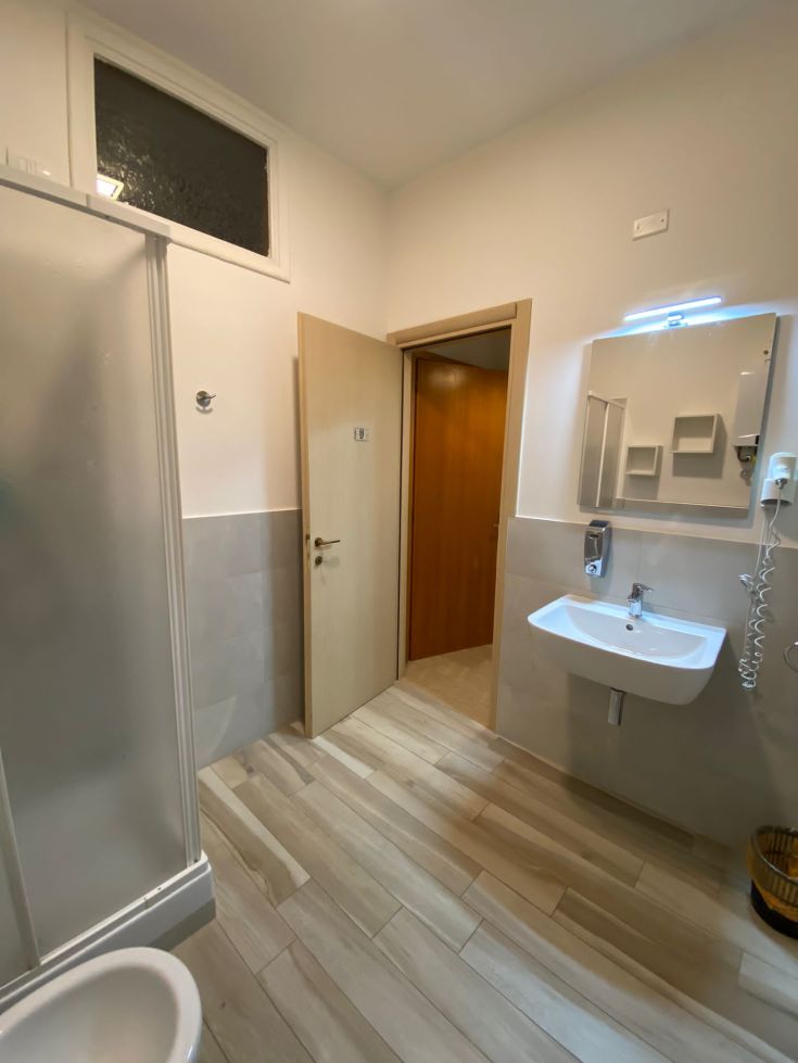 Helles Badezimmer mit Dusche und Waschbecken, einfach und funktionell eingerichtet.