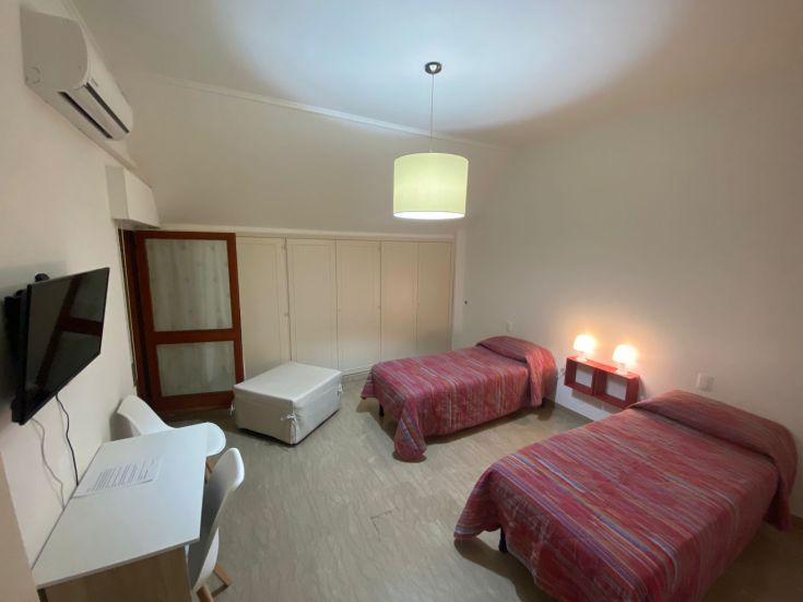 Helle Zimmer mit zwei Betten und einem Schrank, ausgestattet mit einem Fernseher. Zentral gelegen und gut versorgt.