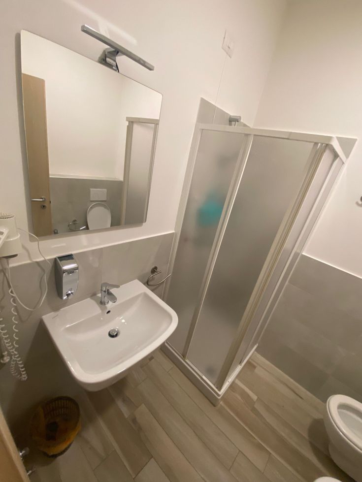 Modernes Badezimmer mit Dusche und Spiegel, in einer Wohnung gelegen. Praktischer und einladender Stil.