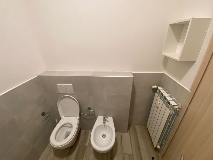 Einfaches und funktionales Badezimmer mit WC und Bidet. Saubere Linien und praktische Einrichtung.