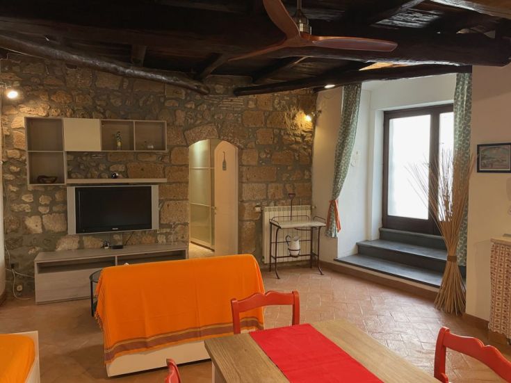 Ambiente confortevole con pareti in pietra e mobili semplici. Luogo ideale per momenti di relax.