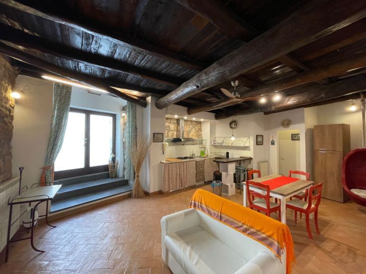 Ambiente semplice con travi in legno, cucina funzionale e area pranzo ben illuminata.