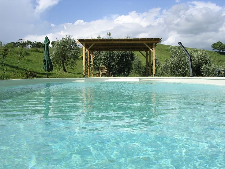 Historic building with a pool surrounded by greenery, perfect for a relaxing moment.