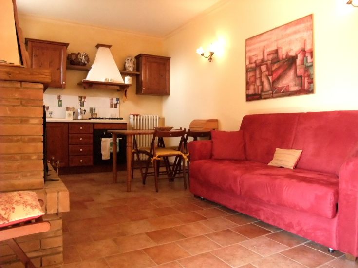 Simple living room with wooden kitchen, red sofa, and dining table.