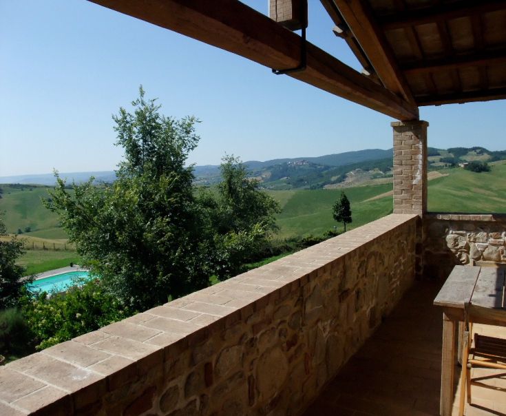 A tranquil scene from an old building with a pool, surrounded by lush countryside.