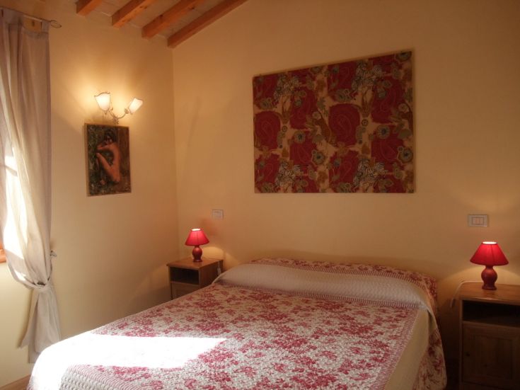 Cozy space in an agriturismo located in an old farmhouse, featuring simple furnishings and views of the surrounding landscape.