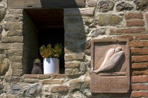 Ein Steinfenster mit einer Topfpflanze und einem Holzelement.