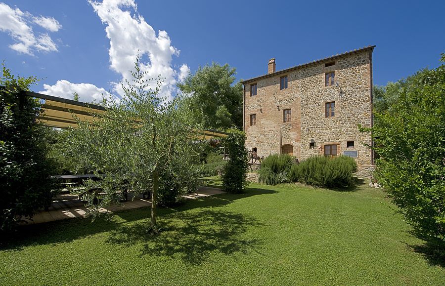 Un casale immerso nel verde, con un giardino spazioso e diverse piante ornamentali.