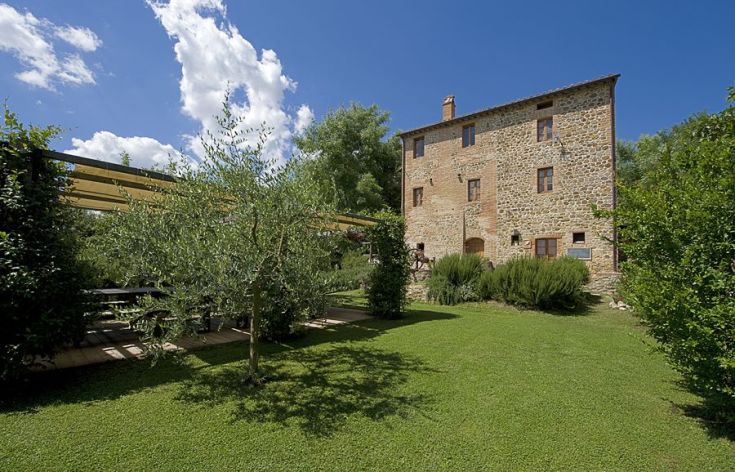 Ein Landhaus umgeben von Grün, mit einem geräumigen Garten und verschiedenen Zierpflanzen.