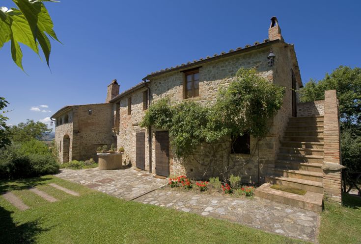 Ein typisches Steinhaus mit einem gepflegten Garten und klarem Himmel.