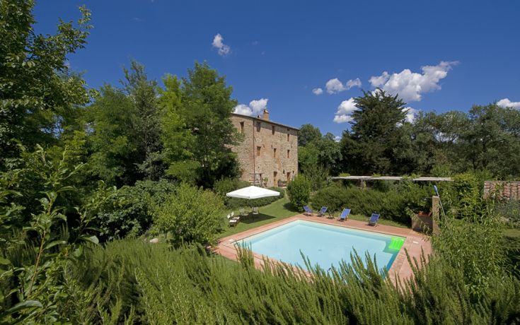 Eine ruhige Szene mit einem Pool inmitten üppigen Grüns, umgeben von Bäumen und einem klassizistischen Gebäude.